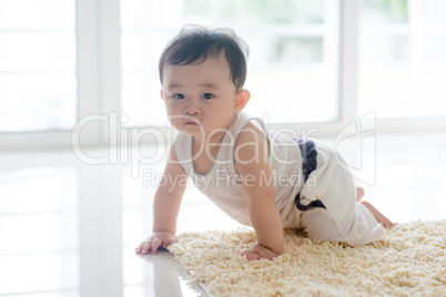 Healthy baby boy crawling on carpet.