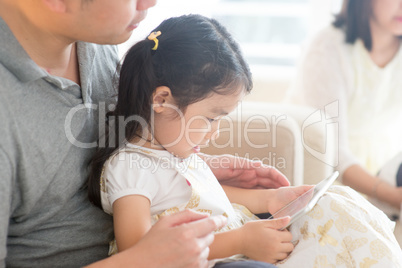 Father and daughter playing with digital tablet.