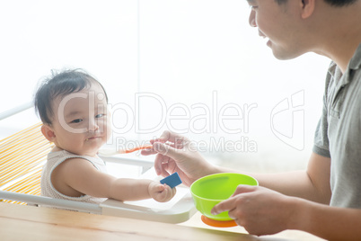 Father feeding toddler solid food.