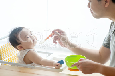 Father feeding baby food.