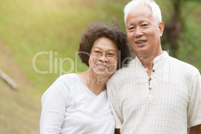 Elderly Asian couple smiling outdoor.