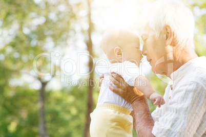 Grandfather and grandson kissing outdoors.