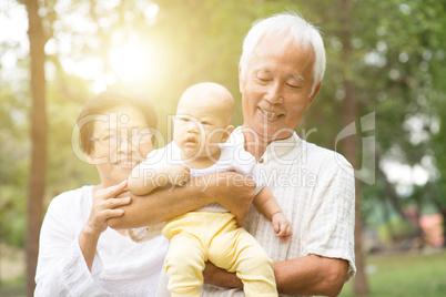 Grandfather, grandmother and grandchild outdoors.