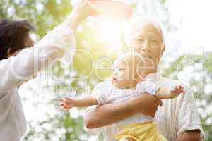 Grandparents playing with grandson at park.