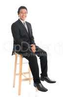 Full body Asian businessman sitting on high chair