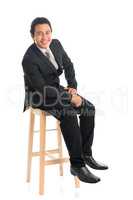 Full body Asian businessman seated on chair