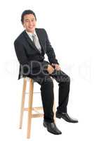 Full body Asian businessman seated on high chair
