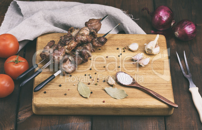 pieces of grilled pork on a grill lie on a wooden board with spi