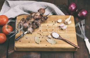 pieces of grilled pork on a grill lie on a wooden board with spi