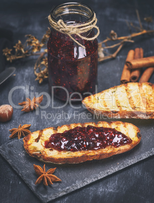 raspberry jam with a glass jar and slices of white bread