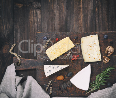 pieces of different cheeses on a brown wooden board: brie, roque