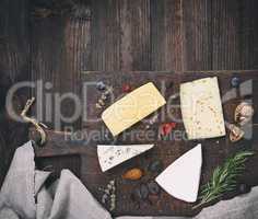 pieces of different cheeses on a brown wooden board: brie, roque