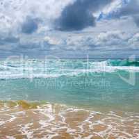 Sandy beach of the tropical ocean and the overcast sky with dram