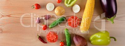 A set of vegetables laid out on a wooden table. Wide photo.