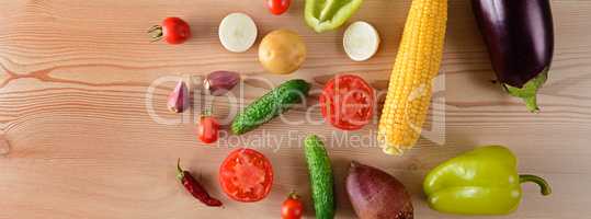A set of vegetables laid out on a wooden table. Wide photo.