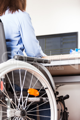 Invalid or disabled woman sitting wheelchair working office desk computer