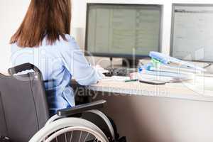 Invalid or disabled woman sitting wheelchair working office desk computer