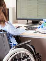 Invalid or disabled woman sitting wheelchair working office desk computer