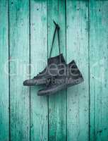 textile sneakers hanging on a green wooden wall
