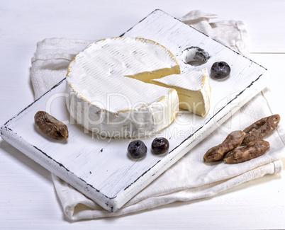 round Camembert cheese on a white wooden board