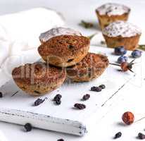 baked round muffins with raisins on a white wooden board