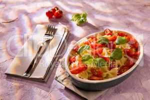 Italian Farfalle pasta with tomatoes and basil over a colored background