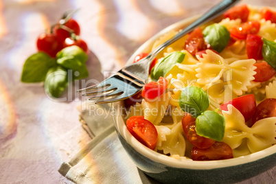 Closeup of Italian Farfalle pasta with tomatoes, basil and fork