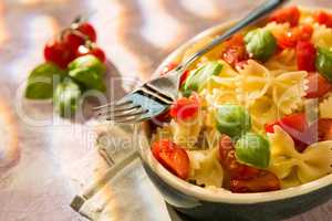 Closeup of Italian Farfalle pasta with tomatoes, basil and fork