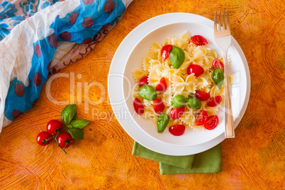 Farfalle pasta with cherry tomatoes and basil seen from above