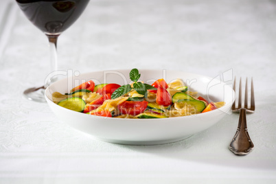 Whole farfalle pasta with zucchini, cherry tomatoes and red onio