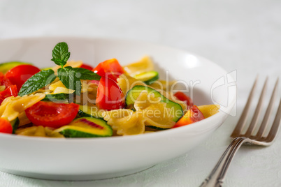 Whole farfalle pasta with zucchini, cherry tomatoes and red onio