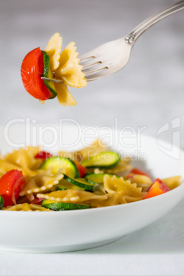 Whole farfalle pasta with zucchini, cherry tomatoes and red onio