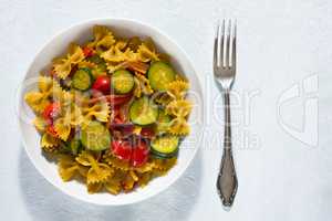 Whole farfalle pasta with zucchini, cherry tomatoes and red onio