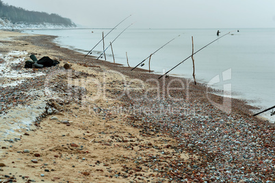 fishing rods on the sea shore, winter fishing at sea, fishing rods placed on the shore of the pond