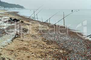 fishing rods on the sea shore, winter fishing at sea, fishing rods placed on the shore of the pond