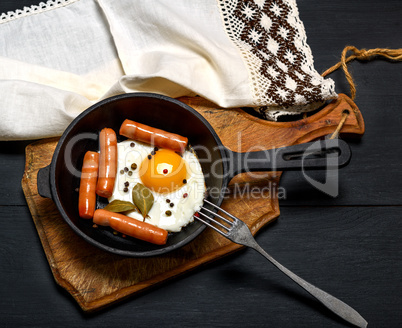 fried chicken egg with sausages in a round frying pan