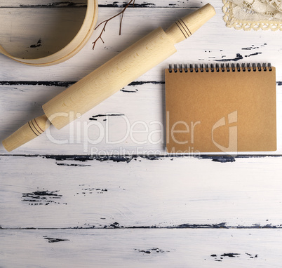 open blank notebook with brown pages and a wooden rolling-pin wi