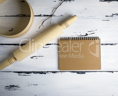 notebook  and a wooden rolling-pin with a round wooden sieve