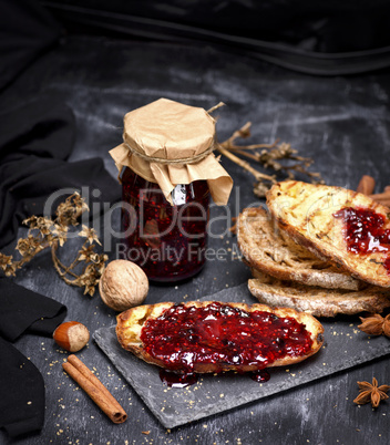toast of white bread with raspberry jam and a glass jar with jam