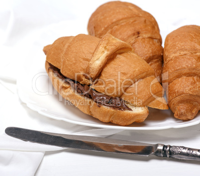 baked croissants with chocolate on a white ceramic plate baked croissants with chocolate on a white ceramic plate