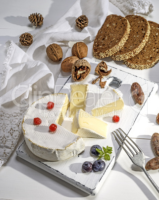 round Camembert cheese on a white wooden board