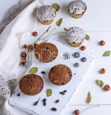 round baked muffins with raisins on a white wooden board