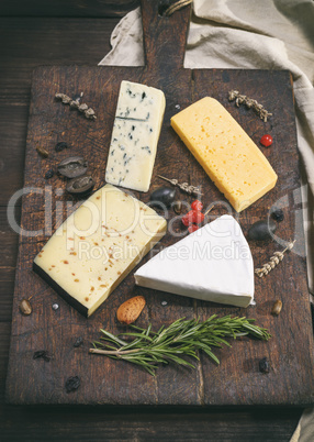 pieces of different cheeses on a brown wooden board
