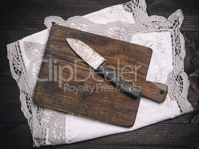 old brown wooden cutting board with handle and knife