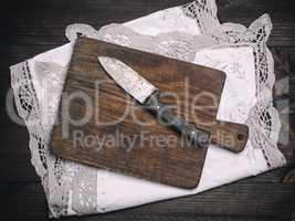 old brown wooden cutting board with handle and knife