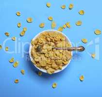 cornflakes in a white ceramic plate and an iron spoon