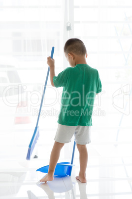 Asian boy sweeping floor