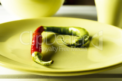 Red and green hot pepper on dish.
