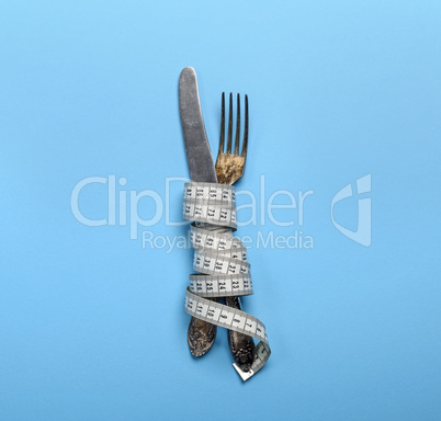 iron fork and knife wrapped in a measuring tape