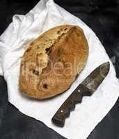 baked loaf of bread with raisins on a white textile napkin